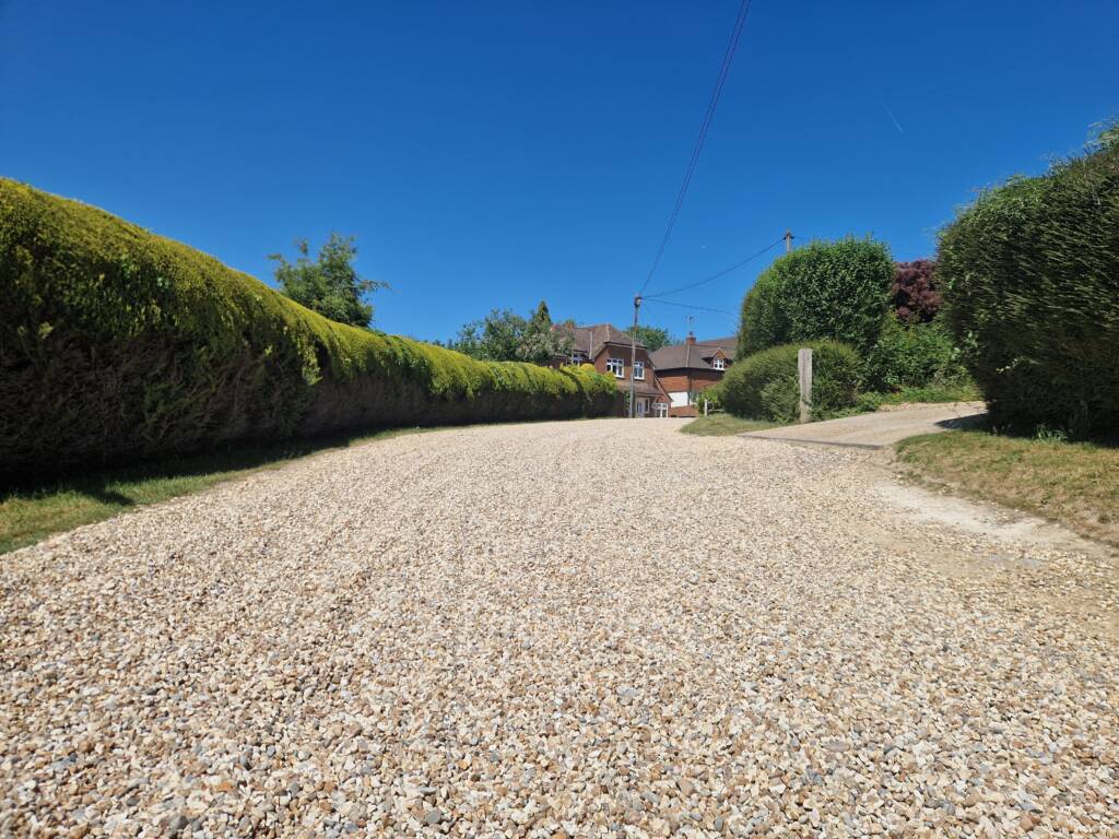 Driveway Construction: Choosing the Right Materials for Style & Durability 1 Long gravel driveway with bushy borders
