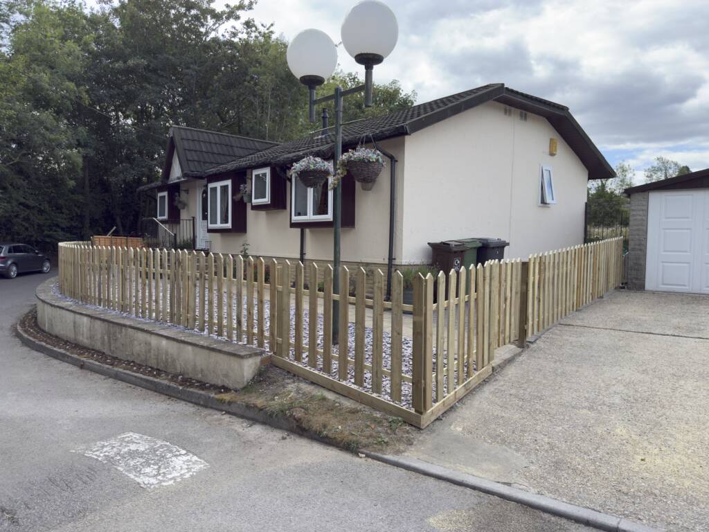 5 Reasons to Upgrade Your Fencing in 2026 1 Wooden picket fence around bungalow driveway