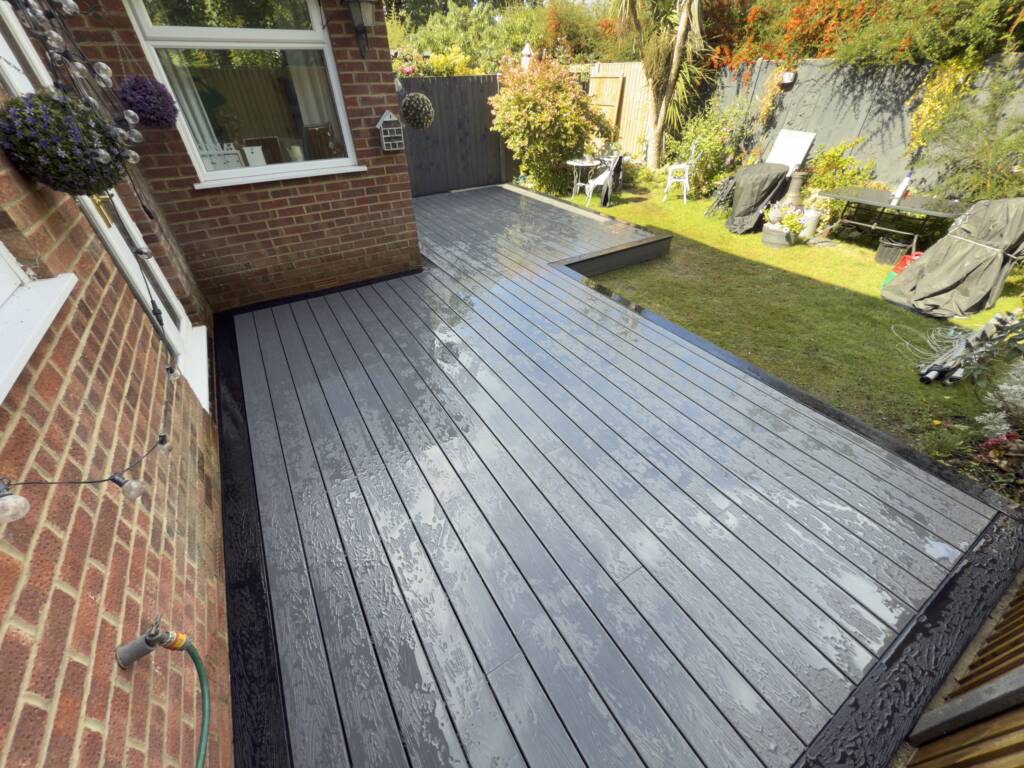 Composite vs. Timber Decking: Which is Best for Your Surrey Garden? 3 Newly laid composite decking in the garden of a house.